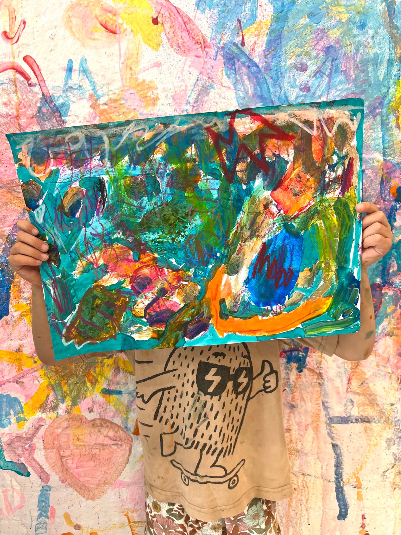 Child holding up large painting